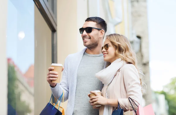 happy couple with shopping bags and coffee in city