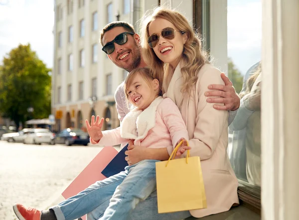 Família feliz com criança e sacos de compras na cidade — Fotografia de Stock