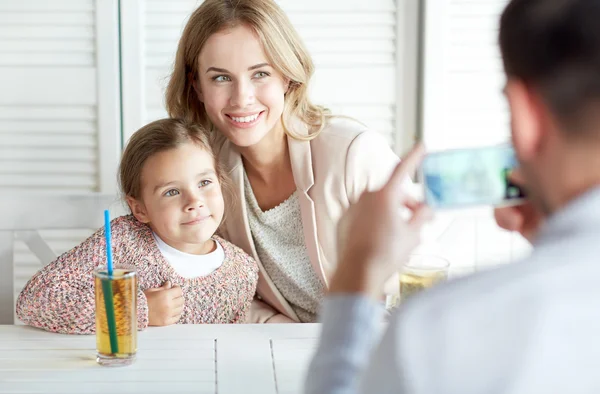 Lycklig familj föreställande av smartphone på restaurang — Stockfoto