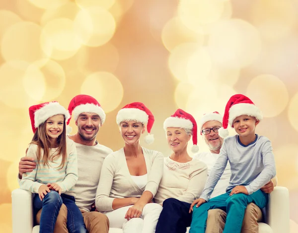 Happy family in santa helper hats sitting on couch — Stock Photo, Image