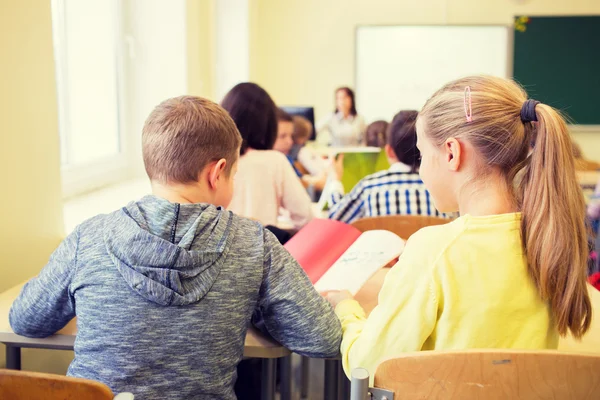 Grupp av skolbarnen skriva prov i klassrummet — Stockfoto