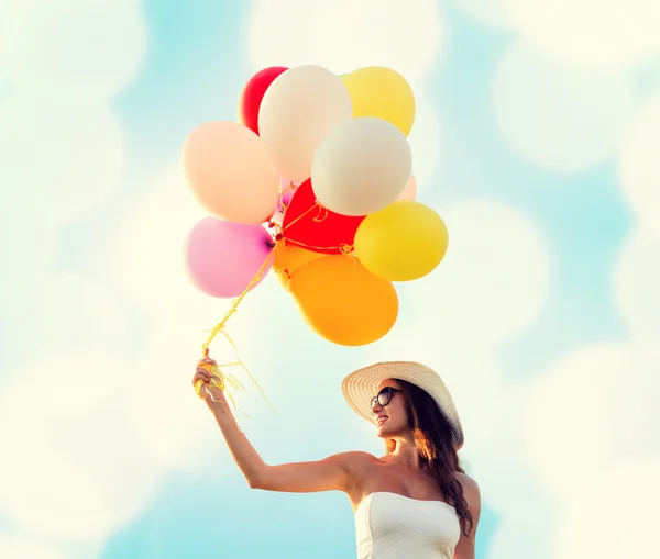 Lächelnde junge Frau mit Sonnenbrille und Luftballons — Stockfoto