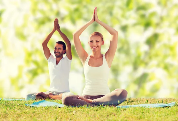 Smilende par som gjør yogaøvelser utendørs – stockfoto