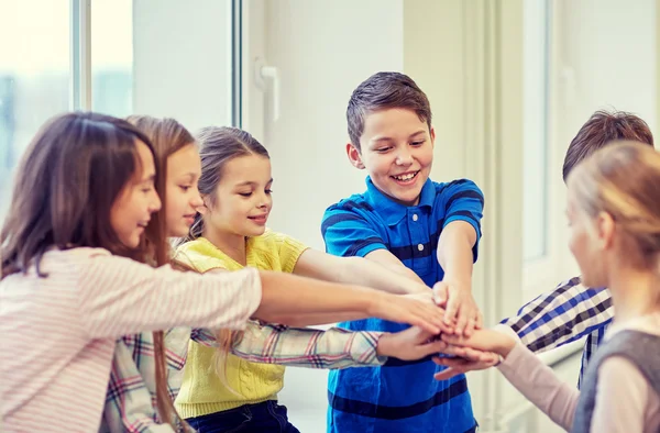 Group of smiling school kids putting hands on top — Stock Photo, Image