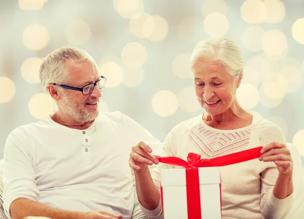 Feliz pareja de ancianos con caja de regalo en casa —  Fotos de Stock