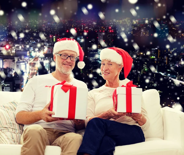 Feliz pareja de ancianos en sombreros de santa con cajas de regalo — Foto de Stock
