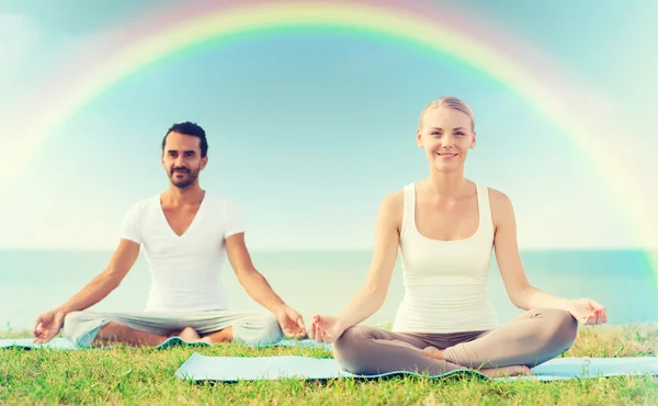 Glimlachend paar oefeningen maken yoga buiten — Stockfoto