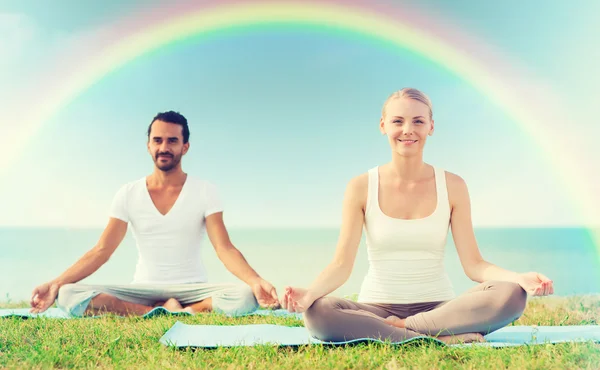 Coppia sorridente fare esercizi di yoga all'aperto — Foto Stock