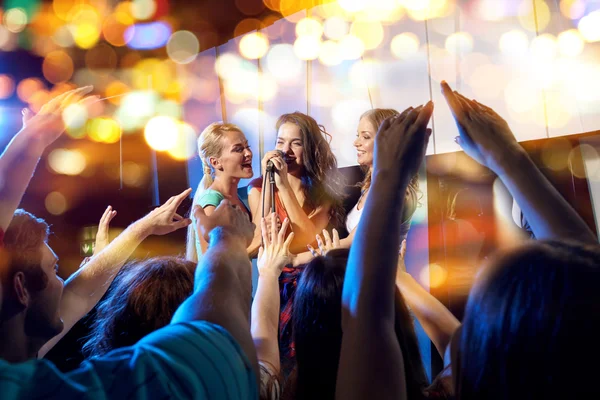 Mujeres jóvenes felices cantando karaoke en el club nocturno —  Fotos de Stock