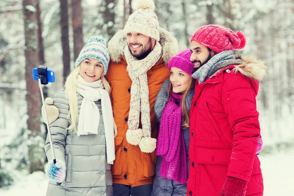 Amis souriants avec smartphone dans la forêt hivernale — Photo