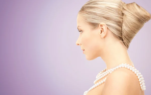 Hermosa mujer con collar de perlas sobre violeta —  Fotos de Stock