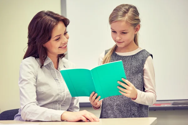 Menina da escola com caderno e professor em sala de aula — Fotografia de Stock