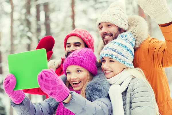 Lachende vrienden met tablet pc in winter forest — Stockfoto