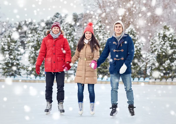 Happy friends ice skating on rink outdoors — Stock Photo, Image