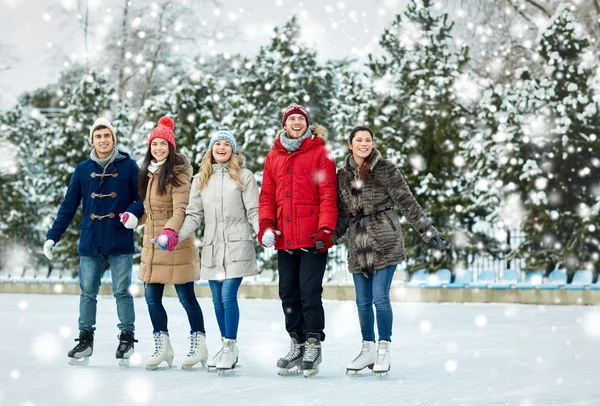 Amigos felices patinaje sobre hielo en pista al aire libre — Foto de Stock