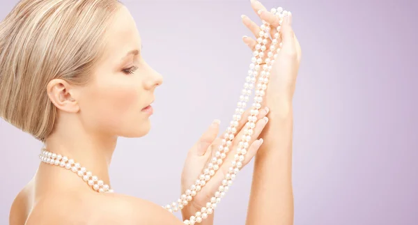 Hermosa mujer con collar de perlas sobre violeta —  Fotos de Stock