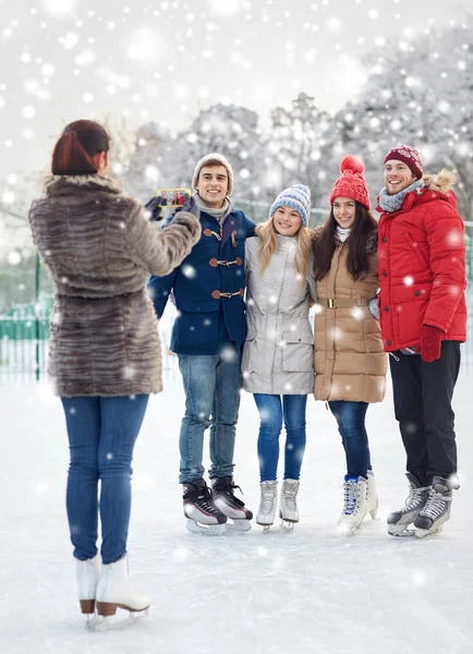 Amigos felices con smartphone en pista de patinaje sobre hielo —  Fotos de Stock