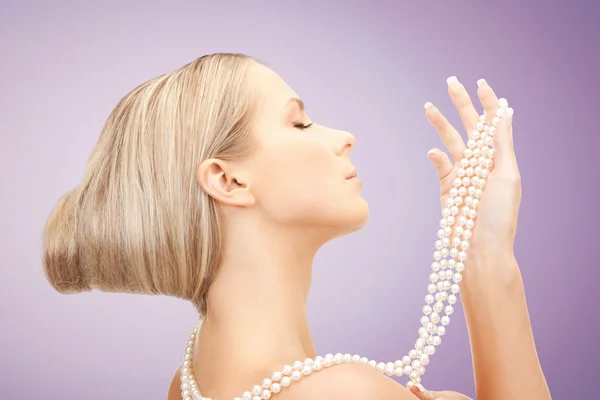 Hermosa mujer con collar de perlas sobre violeta — Foto de Stock