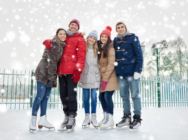 Amigos felices patinaje sobre hielo en pista al aire libre —  Fotos de Stock