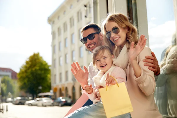 Šťastná rodina s dítětem a nákupní tašky ve městě — Stock fotografie