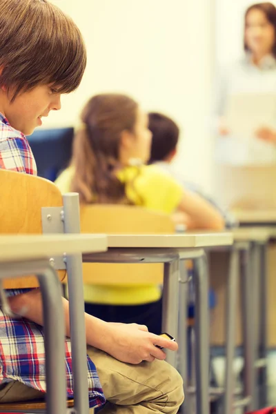 School boy with smartphone on lesson at classroom — Stock Photo, Image