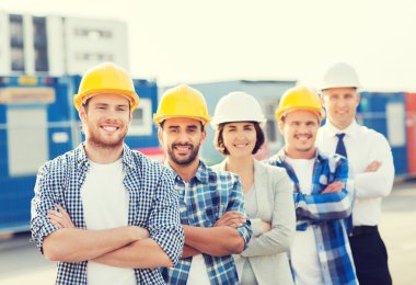 group of smiling builders in hardhats outdoors clipart