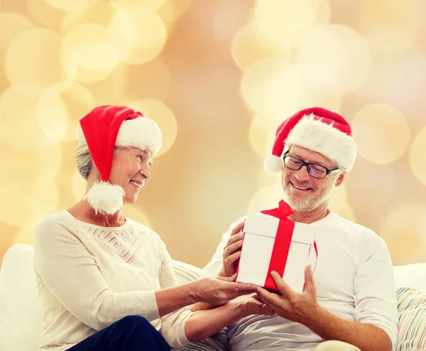 Happy senior couple in santa hats with gift box — Stock Photo, Image