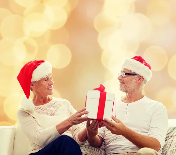 Feliz pareja de ancianos en sombreros de santa con caja de regalo — Foto de Stock