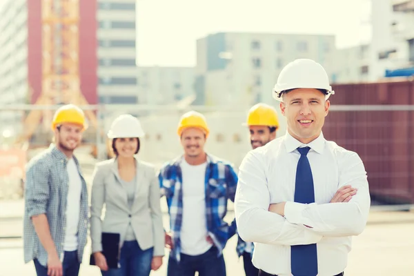 Grupo de construtores sorridentes em hardhats ao ar livre — Fotografia de Stock