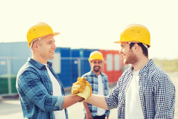 Grupp av leende byggare i hardhats utomhus — Stockfoto