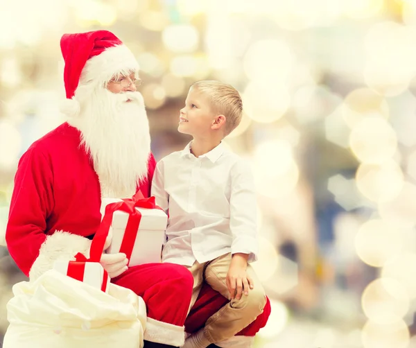 Улыбающийся маленький мальчик с Санта-Клаусом и подарками — стоковое фото