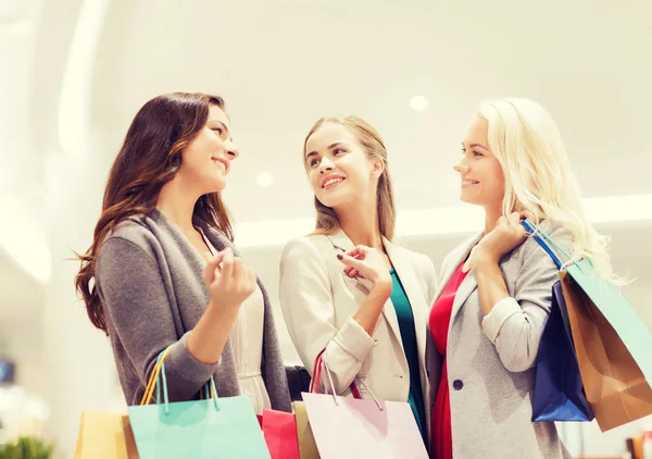 Happy young women with shopping bags in mall — Stock Photo, Image