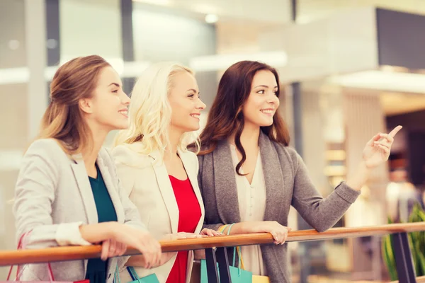 Happy young women with shopping bags in mall — Stock Photo, Image