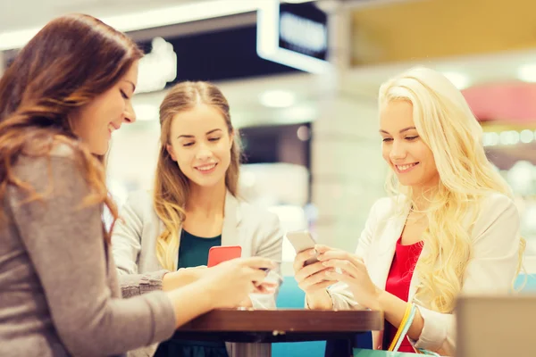 Happy women with smartphones and shopping bags — Stock Photo, Image