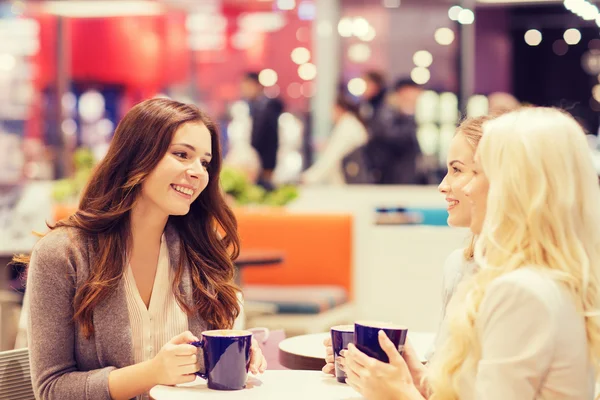 Leende unga kvinnor dricker kaffe i gallerian — Stockfoto