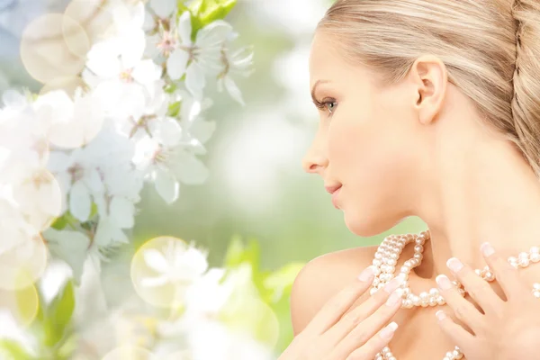 Vrouw met parelketting over kersenbloesem — Stockfoto