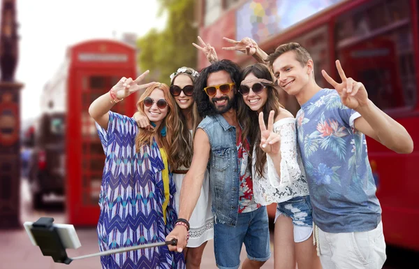 Amigos hippies con smartphone en palo selfie —  Fotos de Stock