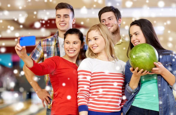 Happy friends with smartphone in bowling club — Stock Photo, Image