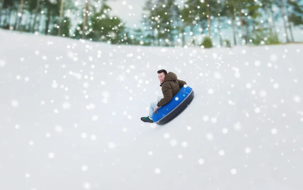 Szczęśliwy młody człowiek zjeżdżać na śniegu tube — Zdjęcie stockowe