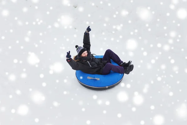 Heureux jeune homme glissant vers le bas sur la neige tube — Photo