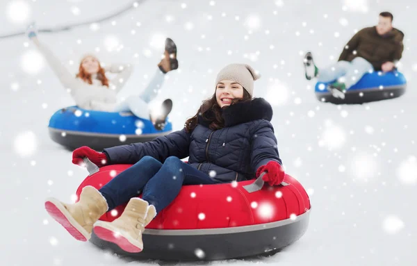 Groep gelukkige vrienden glijdend van op sneeuw buizen — Stockfoto