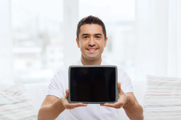 Smiling man showing tablet pc blank screen at home — Stock fotografie