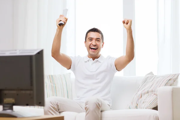 Lächelnder Mann, der zu Hause Sport guckt — Stockfoto