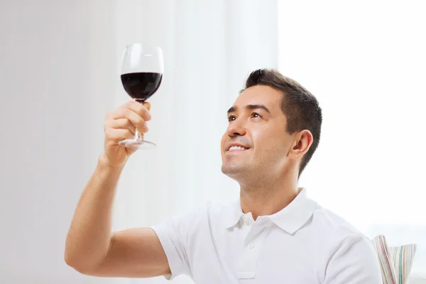 Glücklicher Mann, der zu Hause Rotwein aus Glas trinkt — Stockfoto