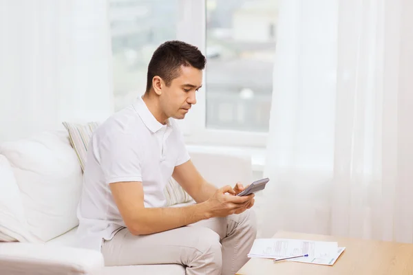 Homme avec des papiers et calculatrice à la maison — Photo