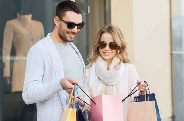 Casal feliz com sacos de compras na vitrine da loja — Fotografia de Stock