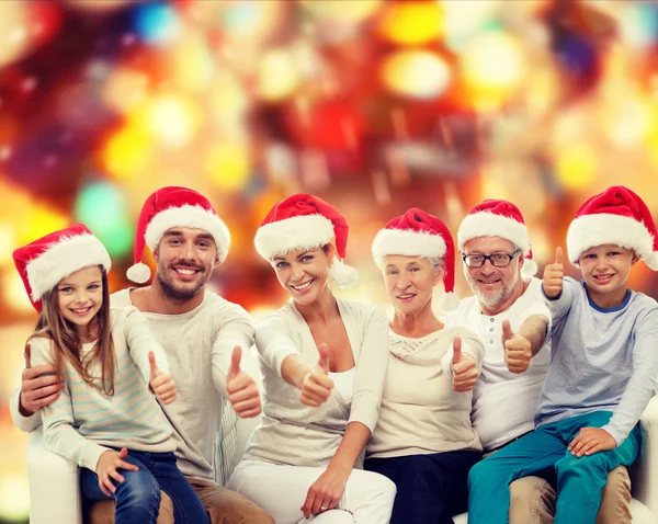 Glückliche Familie mit Weihnachtsmann-Hüten, die Daumen hoch zeigen — Stockfoto