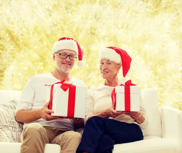 Glückliches Seniorenpaar in Weihnachtsmützen mit Geschenkschachteln — Stockfoto