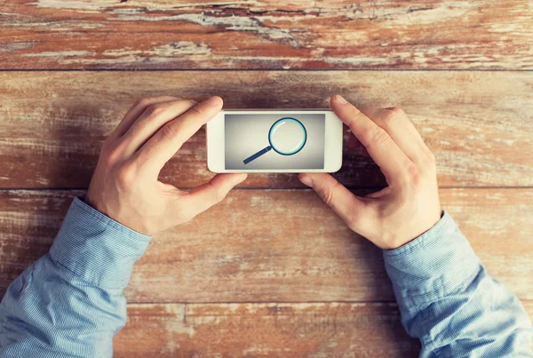 Close up of hands with magnifier on smartphone — Stock Photo, Image