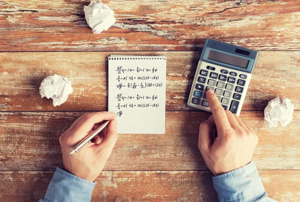 Perto de mãos com tarefa de resolução de calculadora — Fotografia de Stock